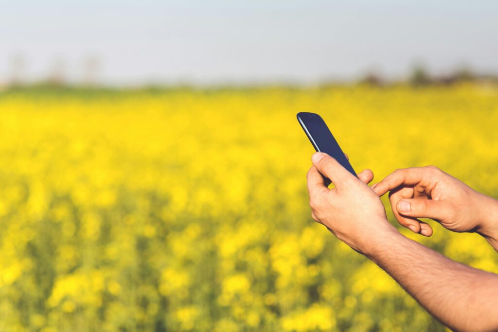 Fermier care folosește telefonul într-un câmp agricol